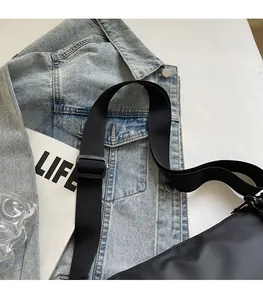 Detail of adjustable wide nylon shoulder strap with plastic buckle on a black crossbody bag