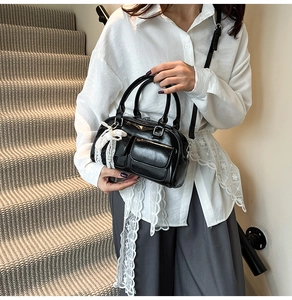 Detail of black patent leather bowling bag with white lace ribbon on handle