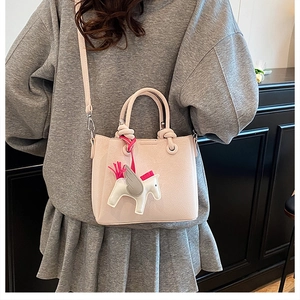 Detailed back view of a light pink bucket bag with a Pegasus charm and leather strap
