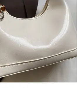 Macro shot of polished cream oil-wax leather texture with gold metal logo on the bag