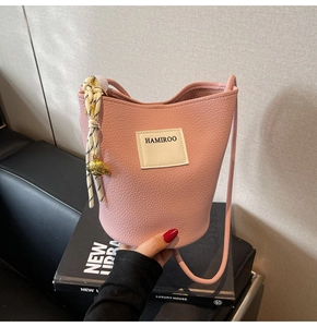 Détail du sac seau rose en cuir grainé avec charm ours et cordon de décoration