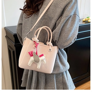Detail of pink bucket bag featuring Pegasus embroidery and lychee leather texture