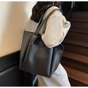 Side view of large black matte tote bag showing the seamless shoulder strap and front pocket