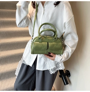 Green leather handbag detail with front flap pockets and adjustable strap for women