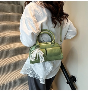 Detail of green PU bowling bag with front flap pockets and lace bow charm on model