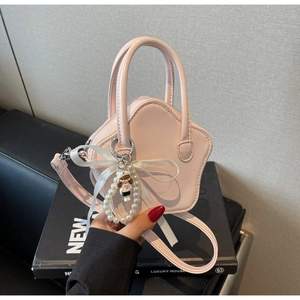 Detail of pink star-shaped handbag with pearl charm and ribbon on decorative books