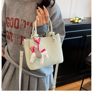 Detail of mint green lychee leather bucket bag with white pegasus charm and thin strap