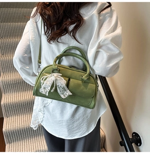 Detail of green bowling handbag with lace bow pearl charm on leather crossbody bag