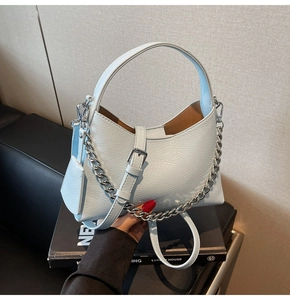Close-up of light blue lychee texture bucket bag with silver chain and mini pouch detail