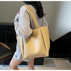 Detail of cream large tote bag with wide strap and side pocket on a female model