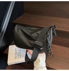 Detail of black nylon messenger bag with adjustable strap on a wooden staircase
