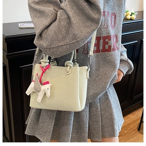 Detail of light green pebbled leather tote bag with unique pegasus charm on model