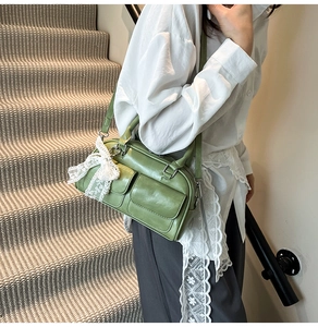 Close-up of green crossbody bowling bag featuring front pockets and lace bow detail
