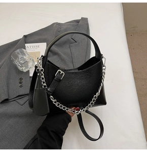 Detail of black litchi grain bucket bag with silver chain handle and leather strap