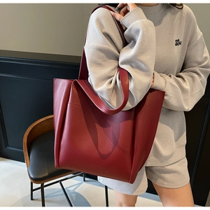 Detail of burgundy leather tote bag with functional exterior pocket and minimalist design