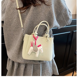 Back view of model carrying a mint green pebbled leather tote bag with pegasus charm