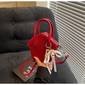 Detail of a bright red mini star-shaped handbag with glossy PU leather and pearl charm