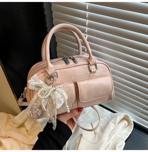 Detail of pink Boston handbag featuring lace pearl bow and front flap pockets