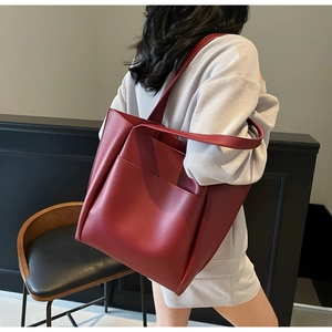 Detail of red large capacity tote bag featuring matte texture and functional side pocket