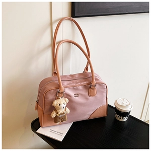 Detailed shot of pink nylon pillow bag with leather corners and cute teddy bear charm