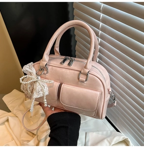 Detail view of pink Boston bag with lace pearl bow charm and dual front pockets