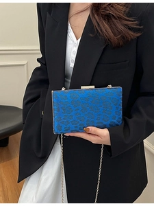 Elegante pochette blu con stampa leopardata e tracolla dorata mostrata su una modella