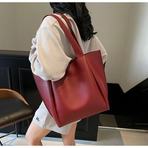 Detailed side view of a large burgundy matte leather tote bag worn by a model