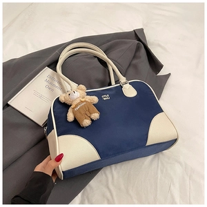 Détail du sac Boston en nylon marine avec finitions en cuir blanc et charm ours marron