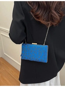 Pochette blu leopardata con catena dorata indossata da una modella in tailleur nero