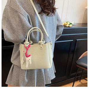 Pale green bucket bag with lychee texture featuring a pony charm and detachable strap