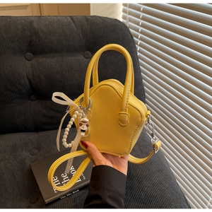 Detail of yellow star-shaped mini bag with pearl chain and bow charm on a sofa