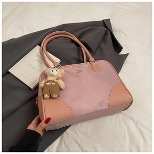 Sac à main patchwork rose avec charm ourson sur blazer gris et livre blanc déco