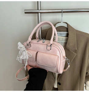 Detail of pink bowling handbag with front pockets and white lace pearl bow charm