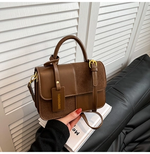 Detail of dark brown leather handbag with fashion metal buckle and textured material