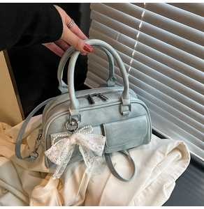 Detail view of a light blue mini bowling bag with white lace bow and pearl charm