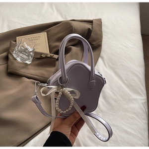 Close-up of lavender star-shaped bag with pearl charm and ribbon detail on bed