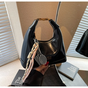 Detail of black dumpling bag with golden buckle and creative decorative charms