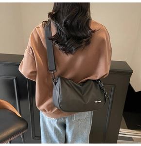 Model wearing black crossbody nylon bag showing the adjustable strap and logo label