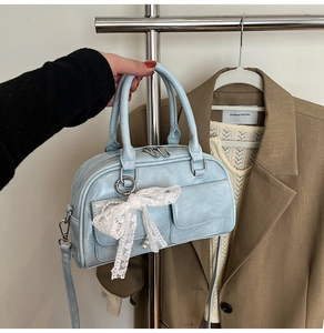 Close-up of light blue bowling bag with white lace bow and pearl charm detail
