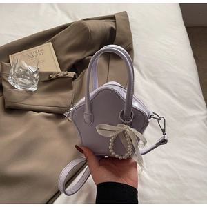 Detail of star-shaped light purple handbag with pearl charm and ribbon on brown jacket
