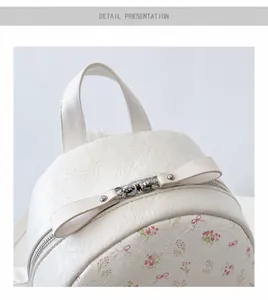 Détails d'un sac à dos crème avec motif floral, double zip en métal et poignée souple