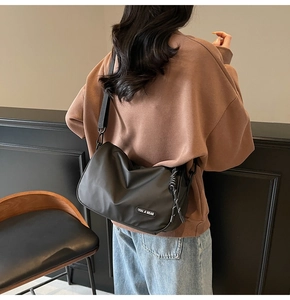 Detail showing a black minimalist half-moon crossbody bag with wide strap and drawstrings