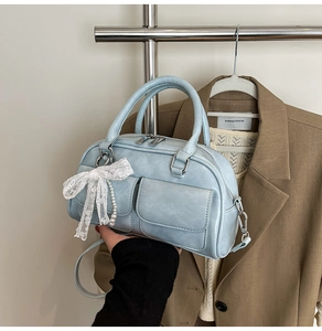 Close-up of light blue bowling bag featuring lace bows, pearls, and dual front pockets