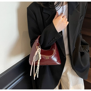 Detailed shot of dark wine red crescent bag with glossy leather and unique decorative charm