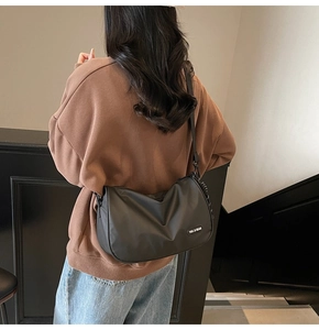 Side view of black nylon messenger bag worn by a model showing size and drape