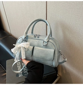 Detail view of light blue glossy bowling bag with a white lace bow pendant and silver hardware