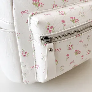 Détail de la fermeture éclair métallique et du motif floral sur le sac à dos blanc