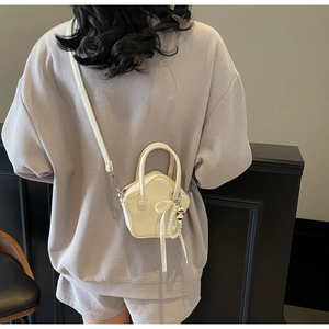 Close-up of star-shaped cream mini bag with pearl and ribbon charms on a model