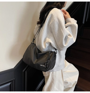 Modern black nylon crescent crossbody bag with adjustable strap on urban stairs