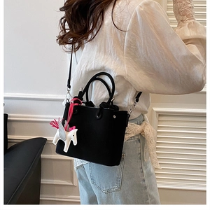 Detail of black lychee grain bucket bag with a white horse charm and detachable strap